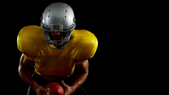 American football player leaning forward holding a ball 4k