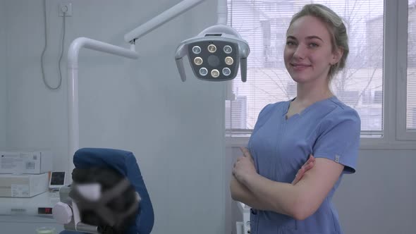 Portrait of Pretty Smiling Female Dentist Assistant Near Dental Chair in Clinic