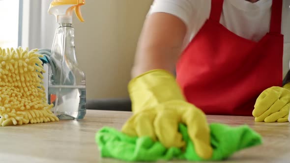 Woman in an Apron and Protective Gloves Washes and Polishes the Countertop Thoroughly