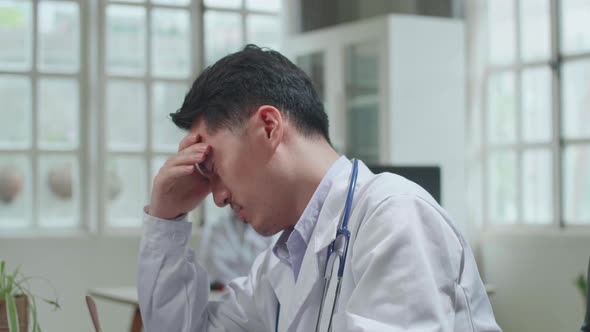 Asian Man Doctor Is Using Desktop Computer And Headache In Workplace. Medical Concept