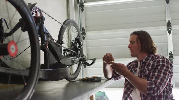 Focused caucasian man repairing bike using tools in garage