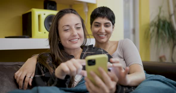 Happy lesbian couple smiling and relaxing on the sofa