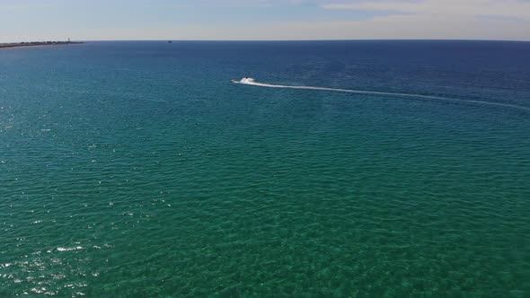 Aerial View of Inflatable Towed Tubes to Roll Tourists on a Tube Tied to Jet Ski Across the Azure