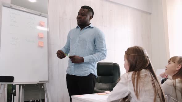 African American Teacher Teaching English Two Primary School Girls