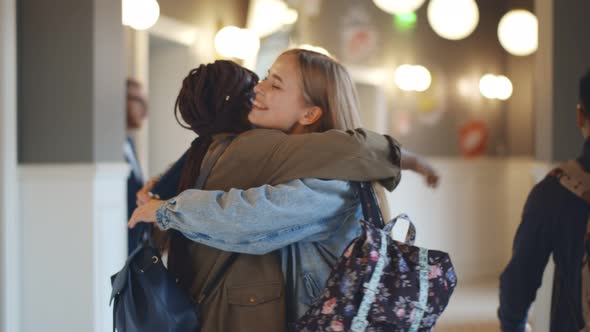 Two Diverse Female College Classmates Meeting and Hugging in School Corridor