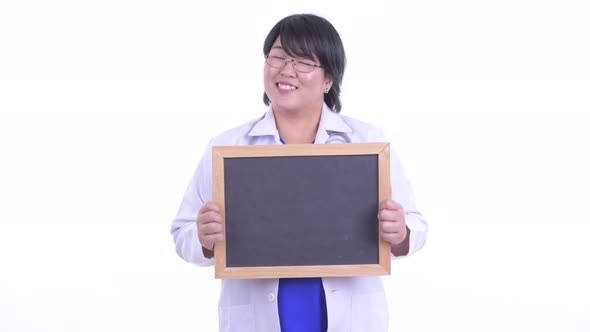 Happy Overweight Asian Woman Doctor Thinking While Holding Blackboard