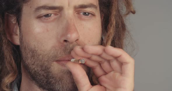 Man with dreadlocks smoking medicinal marijuana on white background