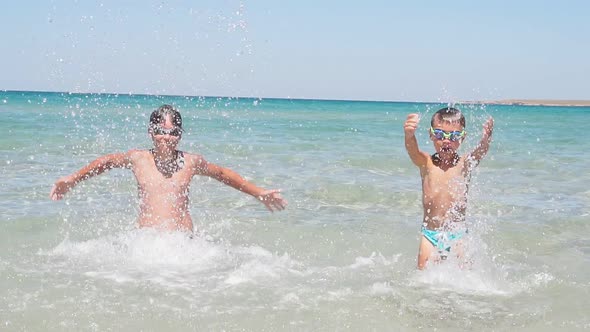 Fun, Happy Children Play in the Sea Creating Splashes of Water. Two Children Splashing in the Clear