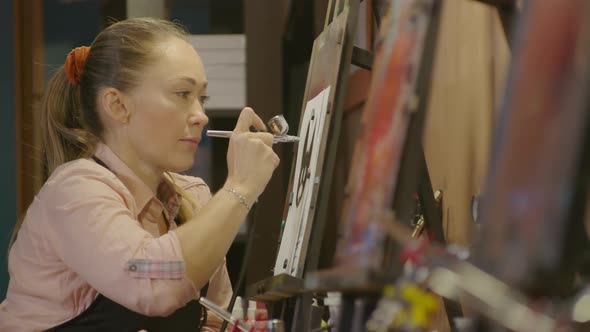 Woman Artist Learns to Paint with Airbrush with Acrylic Dye Paper and Easel