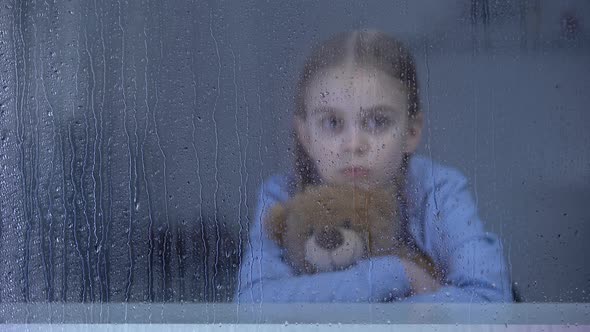 Pretty Little Girl Hugging Teddy Bear Behind Rainy Window, Bullying, Loneliness