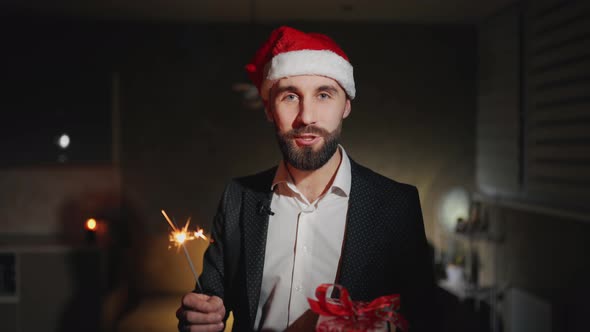 Bearded Businessman with Sparkles and Santa Claus Hat Is Talking Wishes Happy New Year and Looking