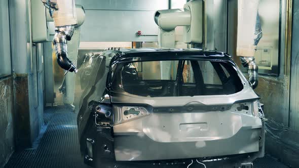 Robotic Arms Spray Painting a Vehicle Body at a Car Production Factory