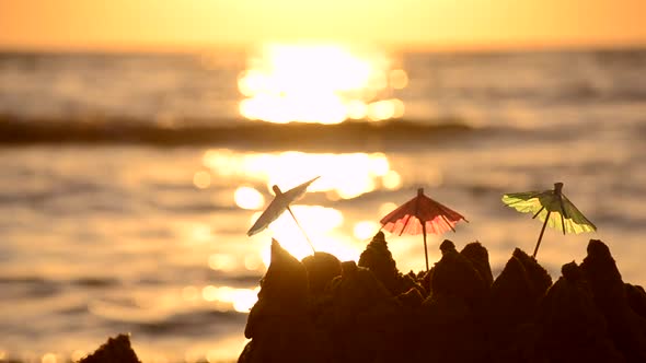 Small Paper Beach Umbrellas Stand in the Sand at Sunrise on the Sandy Beach