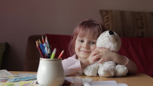 Cute Small Child Girl Sitting at Home Playing and Hugging Her Teddy Bear Toy