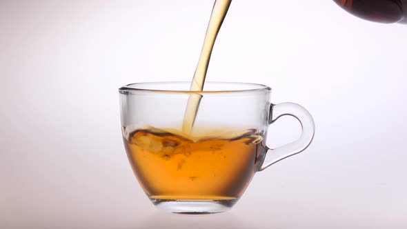 Tea Is Poured From a Teapot Into Small Glass Cup