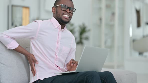 Exhausted African Man with Laptop Having Back Pain at Home 