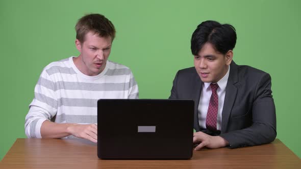 Young Asian Businessman and Young Scandinavian Businessman Working Together with Laptop