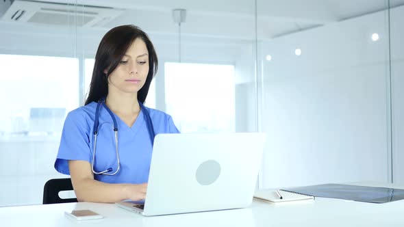 Female Doctor Typing on Laptop in Hospital