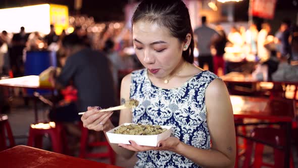 Asian woman eating rice in night market