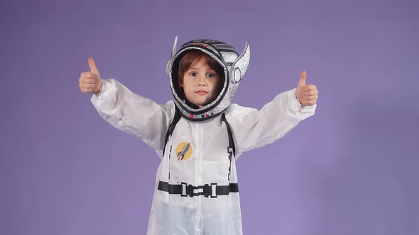 Little Astronaut Kid Boy Wearing White Protective Suit and Helmet Over Purple Background