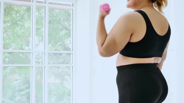 Overweight young woman in sportswear exercising to lose weight at home