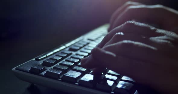 Typing on Keyboard at Night. Dark Background Lighting Close-up