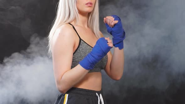 Attractive Blonde Sportswoman in Kickboxing Bandages in Defensive Stance