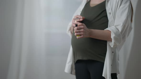 Unrecognizable Expectant with Cigarette and Lighter Standing on the Right Indoors