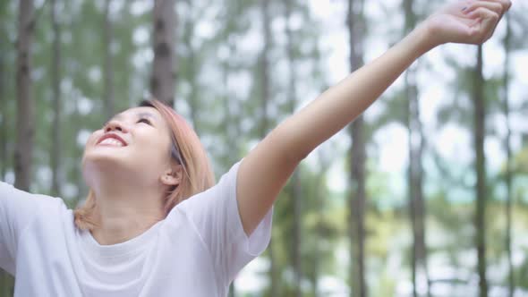 young Asian Athlete woman legs warming and stretching her arms to ready for running on forest trail.