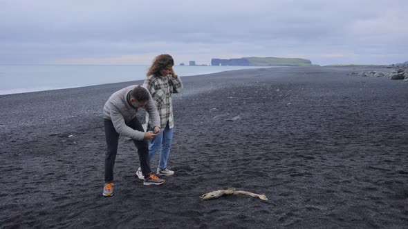 Beautiful Couple Capturing Pics of Fish Skeleton on the Reynisfjara Black Sand