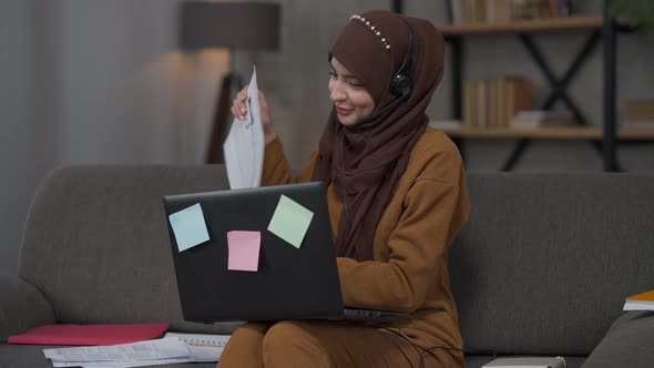 Confident Middle Eastern Charming Woman in Hijab and Headphones Talking at Web Camera in Video Chat