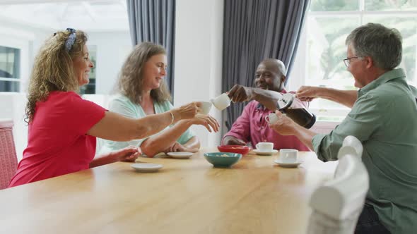 Animation of happy diverse female and male senior friends drinking coffee at home