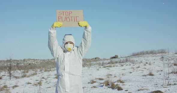 Man Wore in Protective Suit Raise Stop Plastic Sign on Abandoned Place in Winter