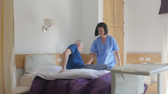 Slow Motion of Asian Female Doctor Helping Elderly Man Getting Up From Bed in the Hospital