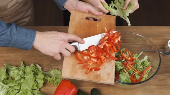 Cooking Salad at Home Man Hands Adding Chopped Red Pepper Slices To Glass Salad Bowl