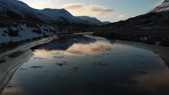 Stunning Nature of Iceland. Aerial View of Glacial River Under Snow Capped Hills and Sky Reflection