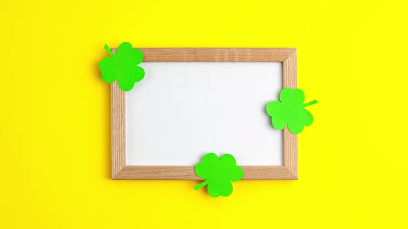 Stop motion animation of green paper clovers flat lay on wooden frame with white copy space alt