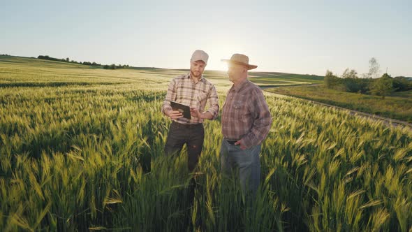 A Man is Showing an Old Farmer Information on a Tablet