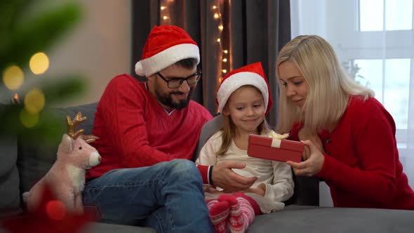 Family Open Gift Box with Magic Luminous Light Next to Christmas Tree at Home