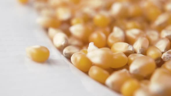 Slow Motion Pour uncooked corn seeds into a white popcorn bowl. 