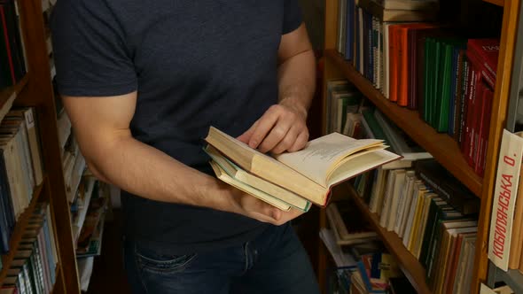 Man Standing In The Library And Turning The Book Pages