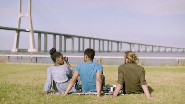 Back View of Young People Sitting on Meadow and Talking