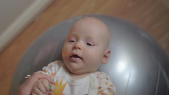 A Baby Girl Lying on a Big Silver Gymnastic Ball