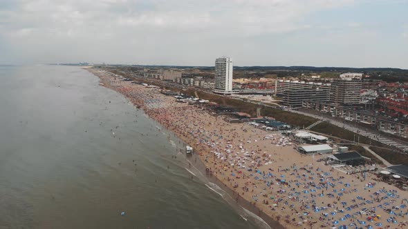 Aerial footage of a crowded beach along near Zandoort, Netherlands of the North Sea.