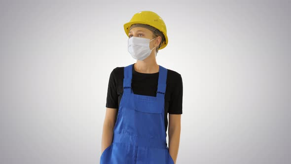 Young Woman in Yellow Hardhat and in Medical Mask Walking on Gradient Background