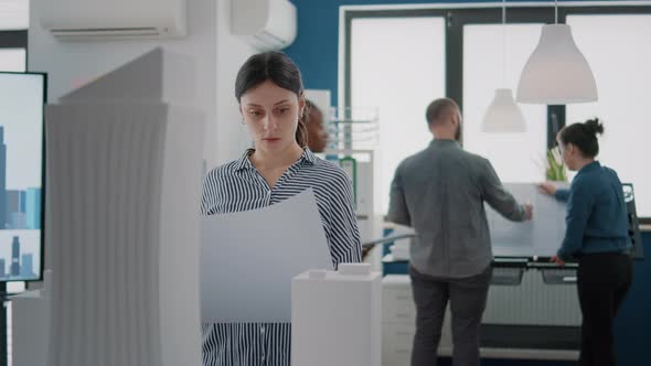 Portrait of Woman Architect Studying Blueprints Plans on Paper to Design Building Model