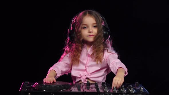 Girl in Headphones Plays on Turntable. Black Background, Slow Motion