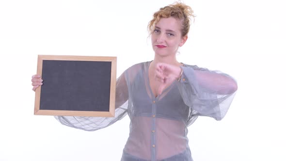 Stressed Blonde Woman Holding Blackboard and Giving Thumbs Down