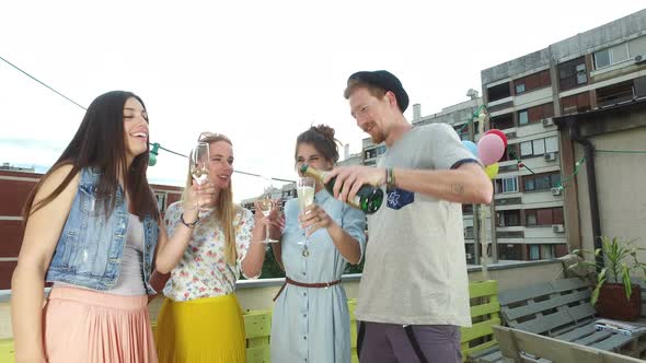 Hipster man pouring champagne to his beautiful female friends