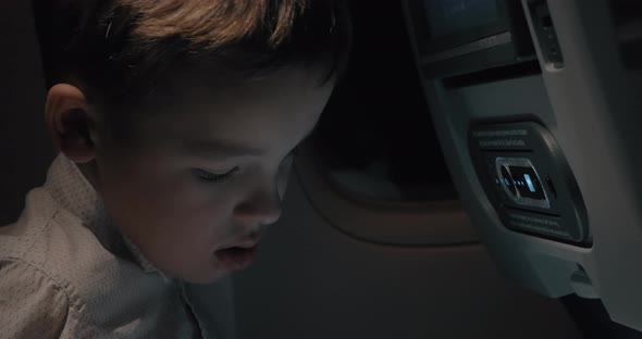 Boy playing chess on touch pad during night flight